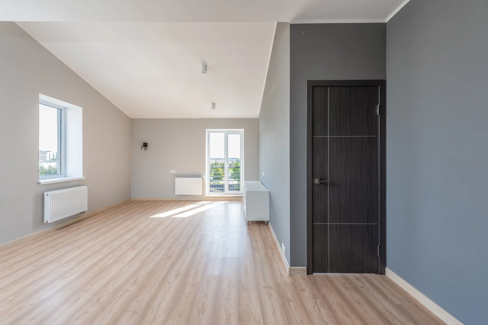 Séjour vide et lumineux avec parquet et grande fenêtre